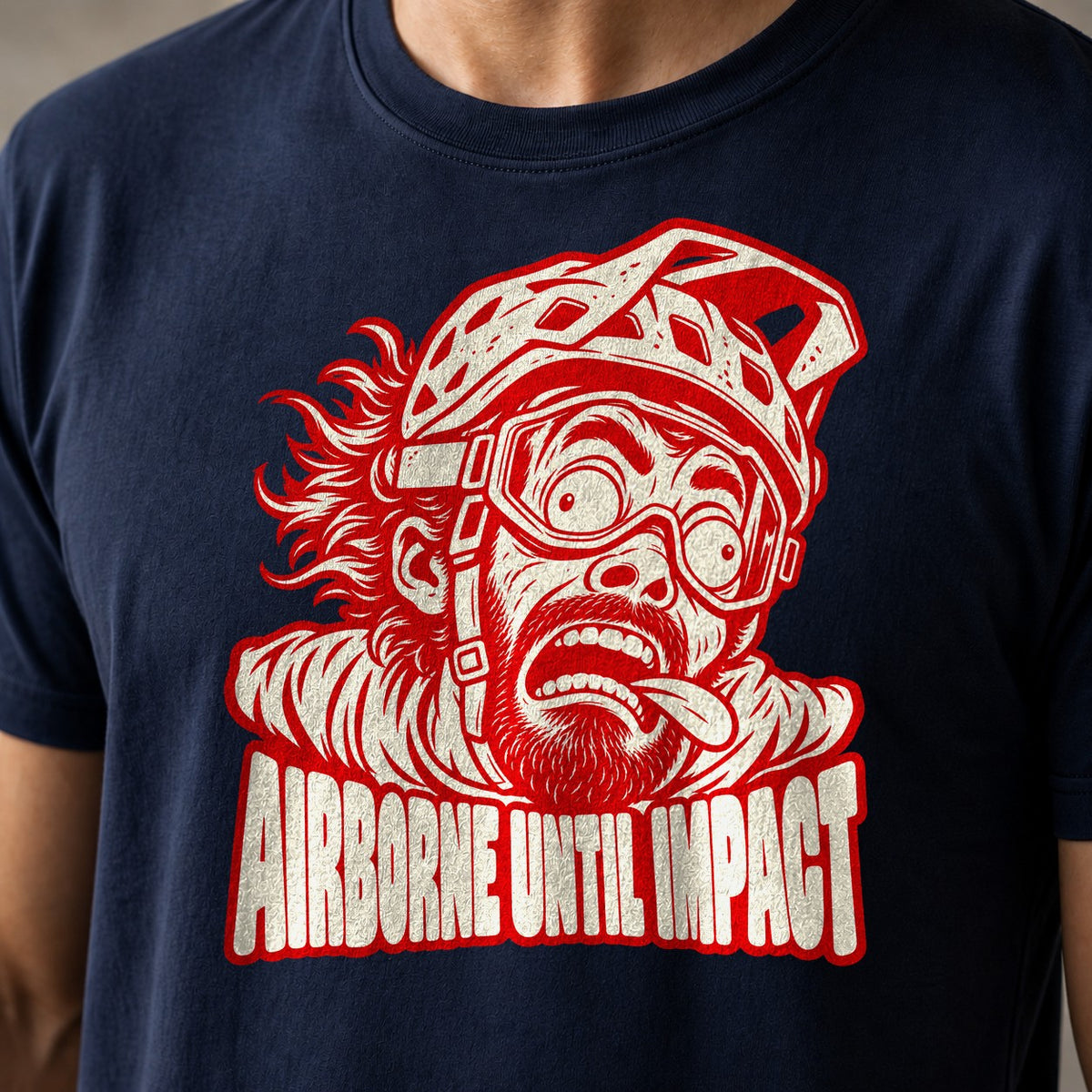 Airborne Until Impact funny mountain bike t-shirt in Navy — screaming mountain biker face mid-air with goggles askew above Airborne Until Impact text — close-up of the print