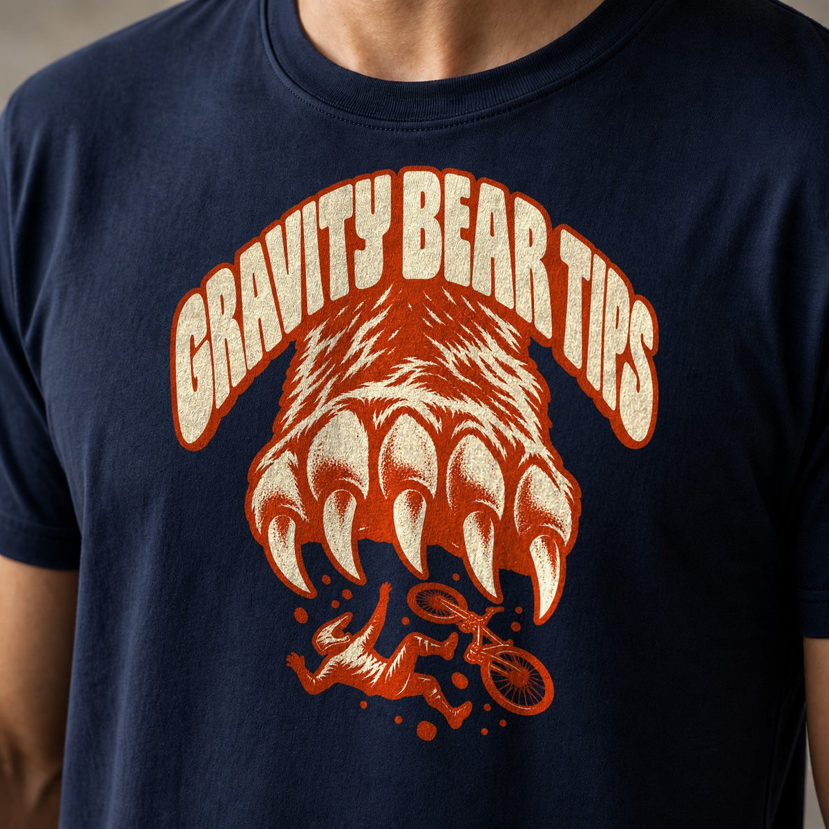 Gravity Bear Tips funny mountain bike t-shirt in Navy — giant bear paw with claws above a small tumbling mountain biker under Gravity Bear Tips — close-up of the print