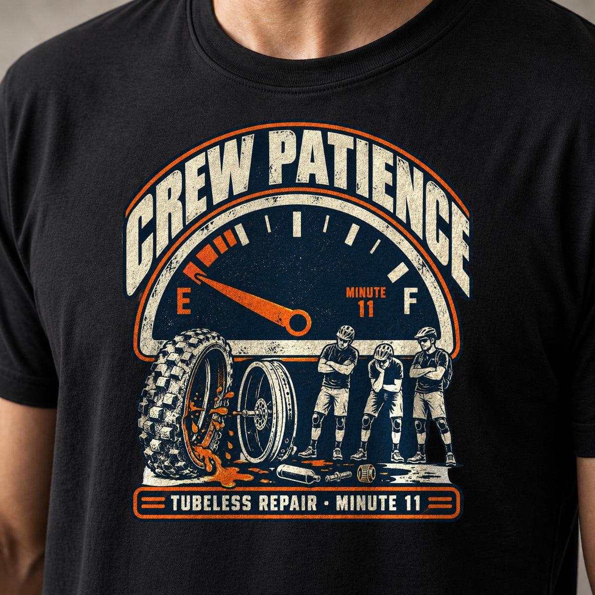 Crew Patience funny mountain bike t-shirt in Black — fuel gauge on empty above a leaking tire and three riders waiting with arms crossed, Tubeless Repair Minute 11 — close-up of the print