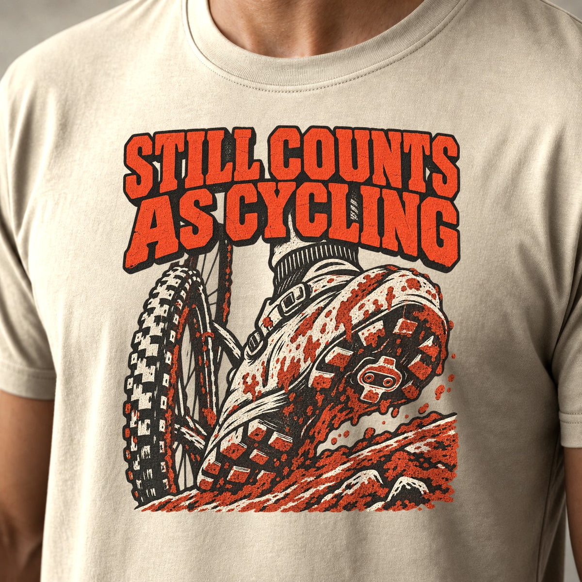 Still Counts As Cycling mountain bike t-shirt in Natural — mud-caked shoe planted on a rocky step beside the front wheel — close-up of the print