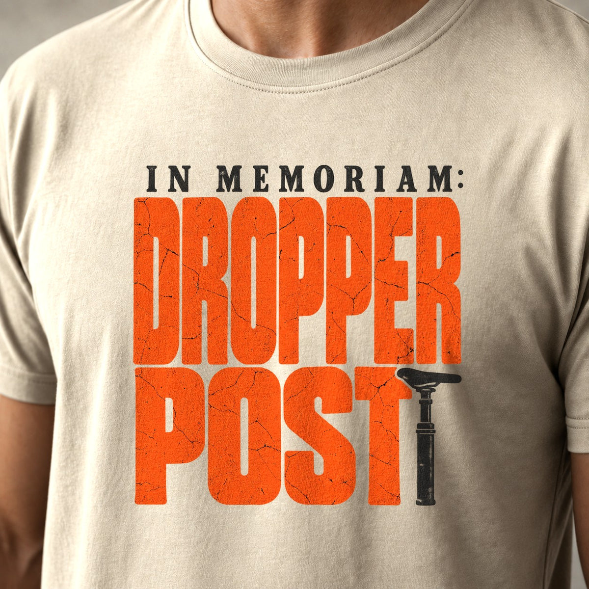 In Memoriam: Dropper Post mountain bike t-shirt in Natural — cracked orange letters with a worn dropper post as the T — close-up of the print