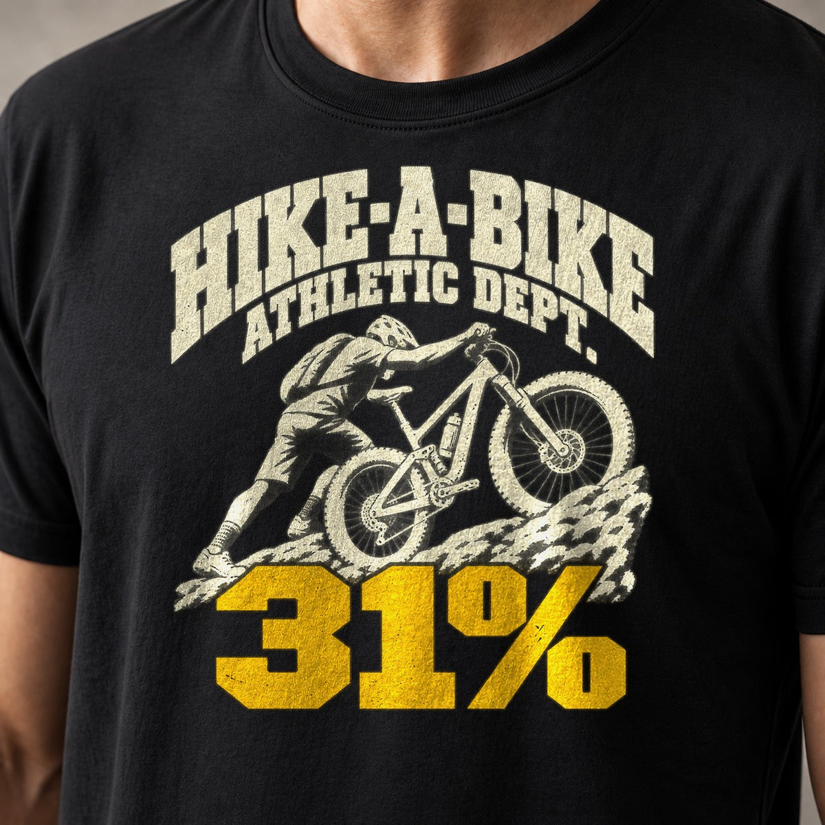 Hike-A-Bike Athletic Dept. 31% funny mountain bike t-shirt in Black — college-style lettering over a rider pushing up a rock face — close-up of the print