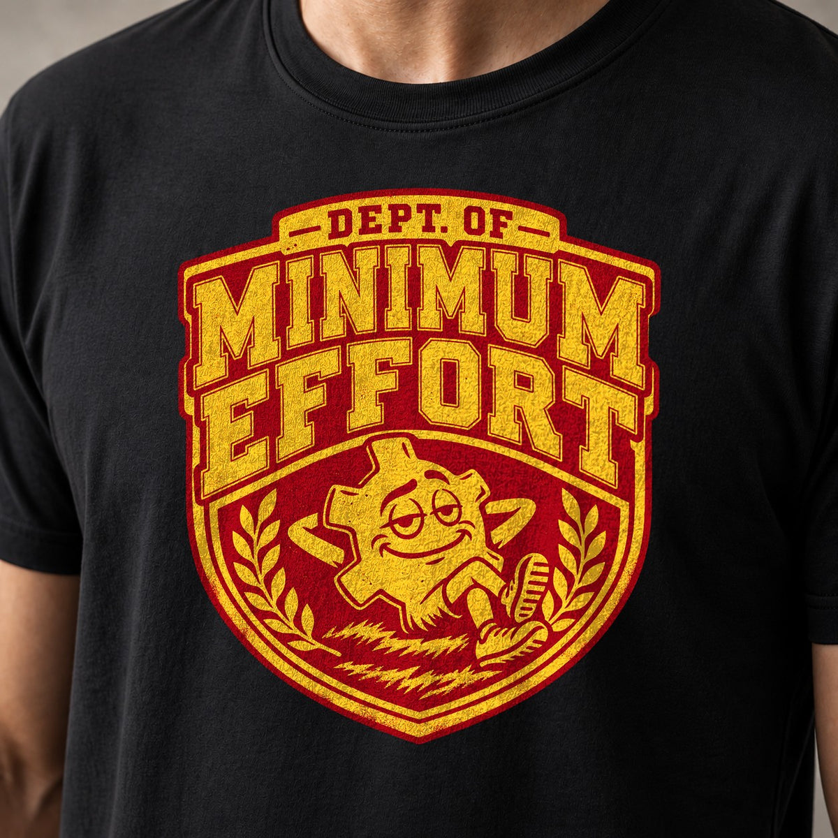 Dept. of Minimum Effort mountain bike t-shirt in Black — varsity crest with a chainring mascot lounging in the grass — close-up of the print
