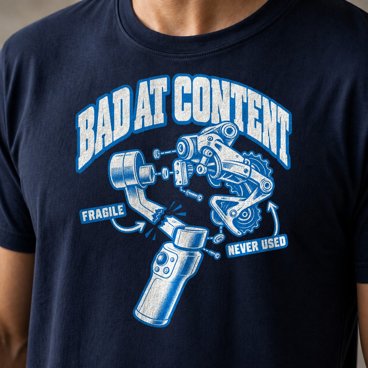 Bad At Content funny mountain bike t-shirt in Navy — exploded diagram of a phone gimbal and rear derailleur labeled Fragile and Never Used under Bad At Content — close-up of the print