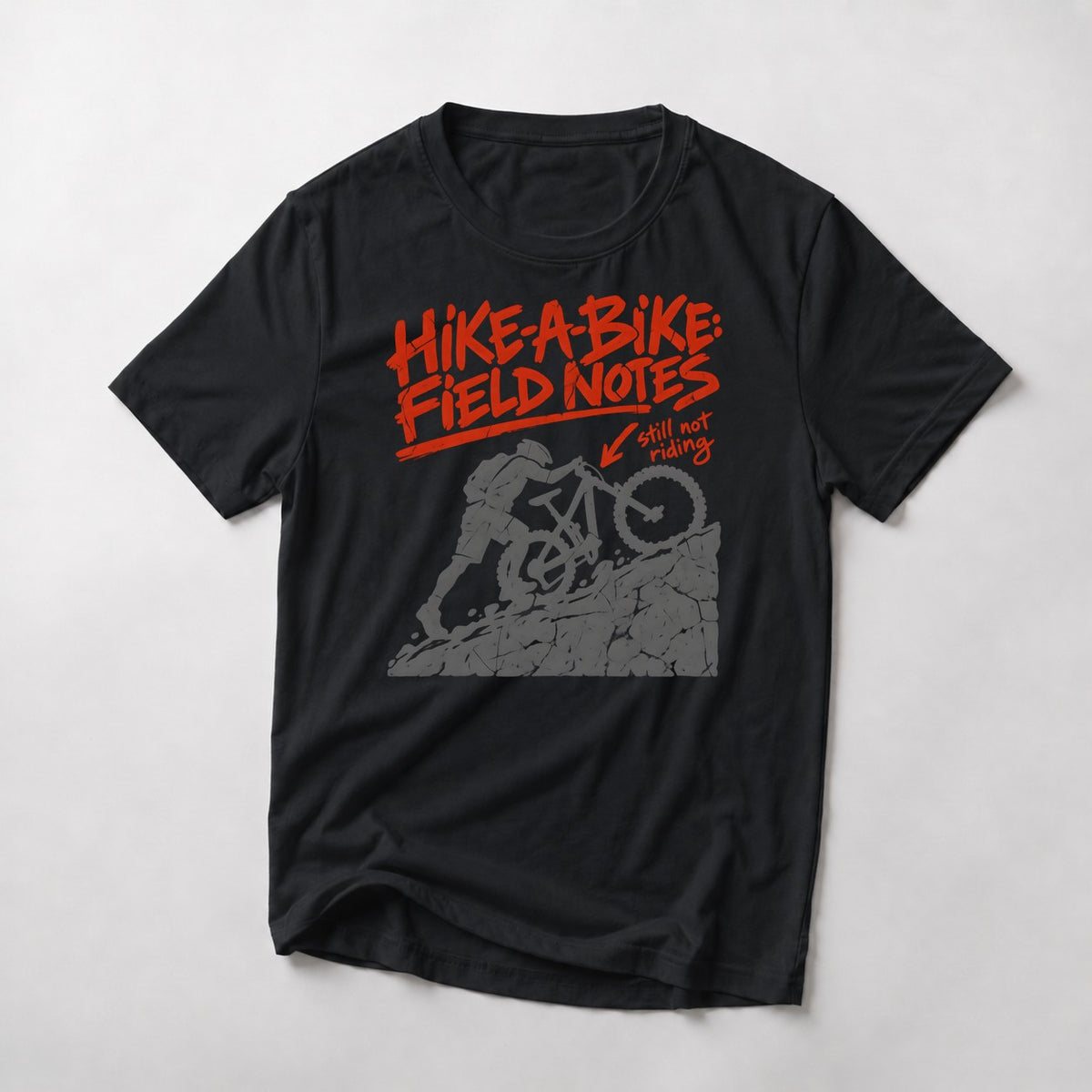 Hike-A-Bike: Field Notes mountain bike t-shirt in Black — rider pushing up a rock face, marked in red as still not riding