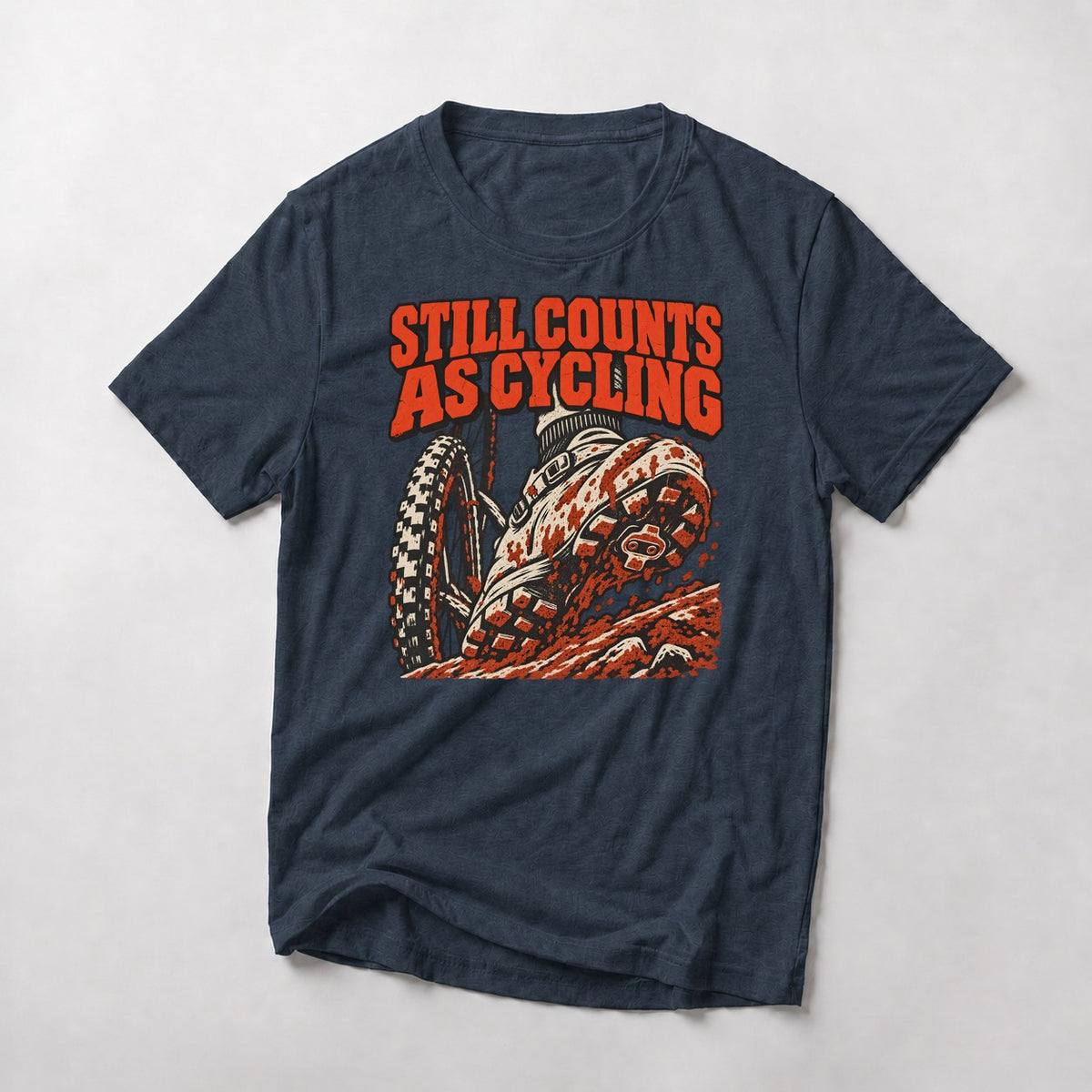 Still Counts As Cycling mountain bike t-shirt in Heather Navy — mud-caked shoe planted on a rocky step beside the front wheel