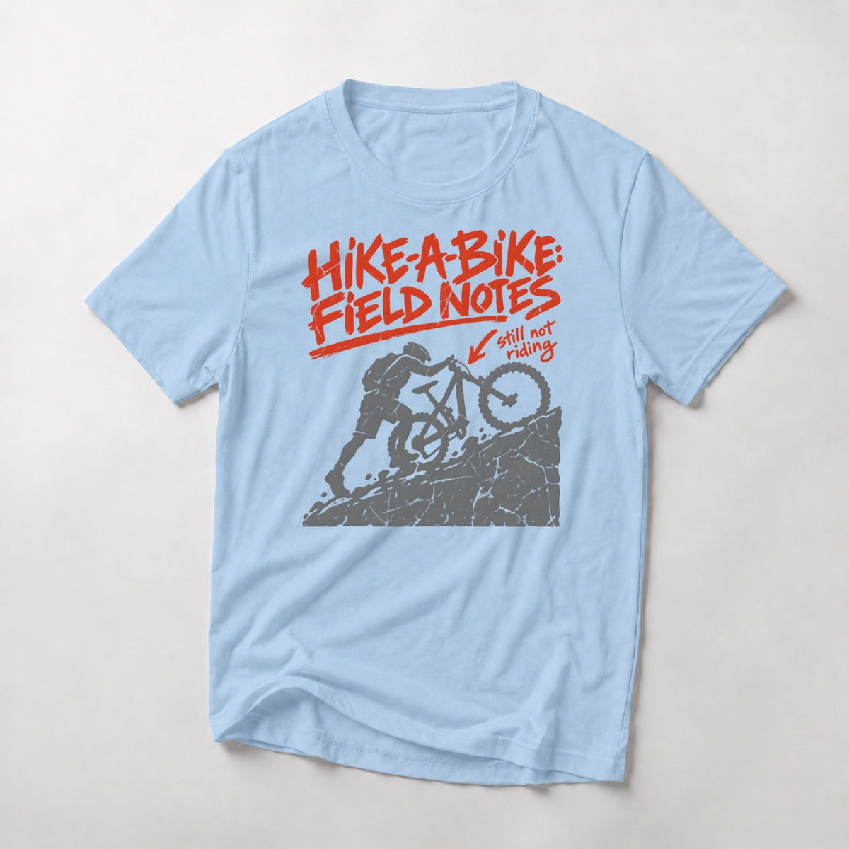 Hike-A-Bike: Field Notes mountain bike t-shirt in Light Blue — rider pushing up a rock face, marked in red as still not riding