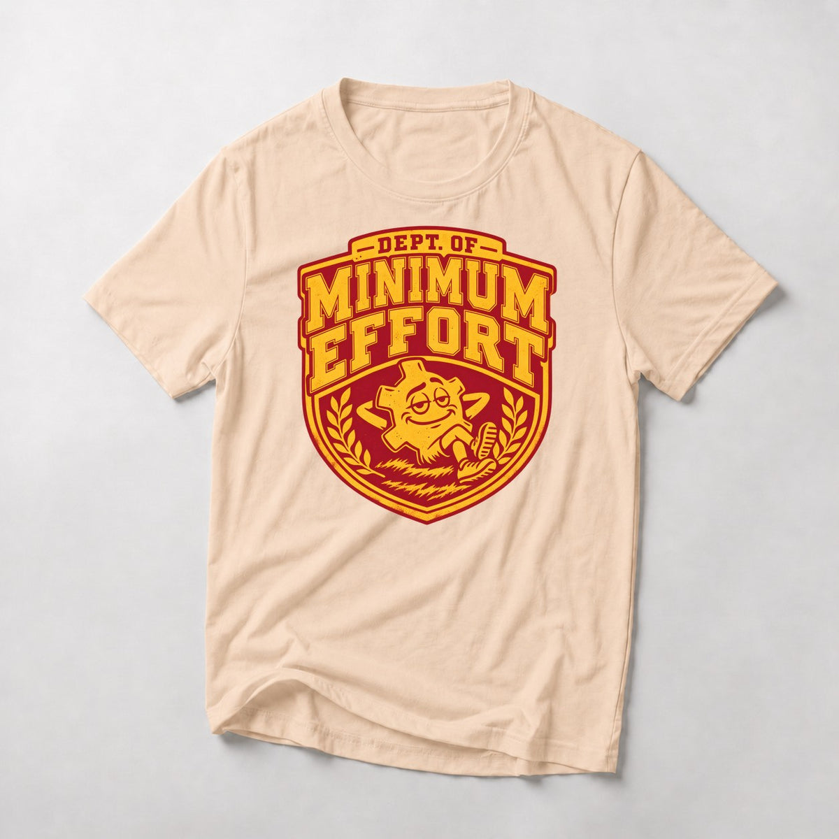 Dept. of Minimum Effort mountain bike t-shirt in Natural — varsity crest with a chainring mascot lounging in the grass