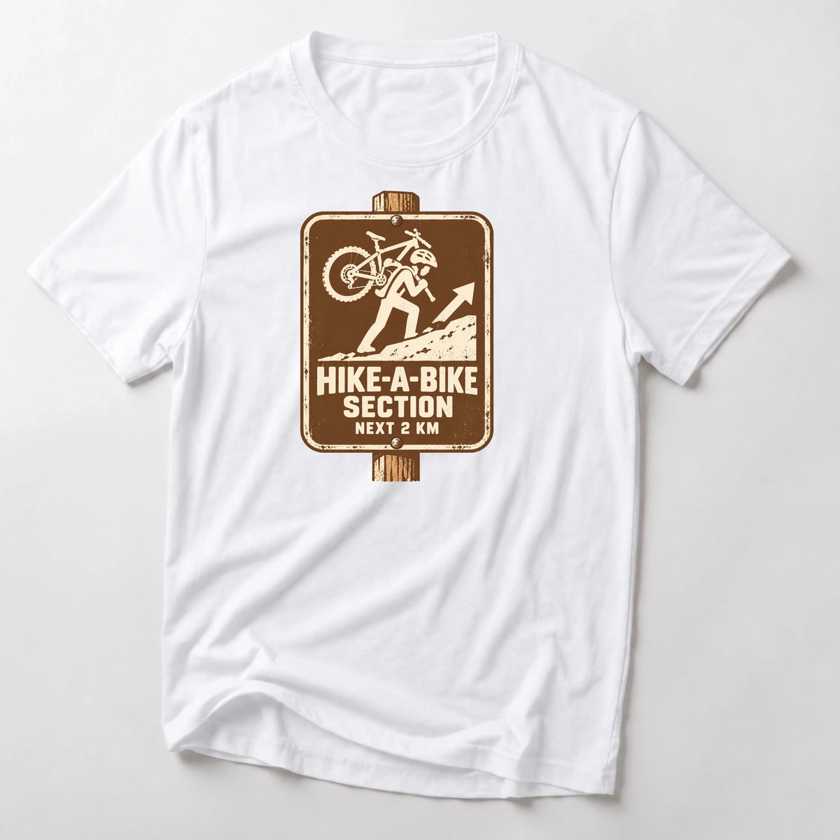 Hike-A-Bike Section Next 2 KM mountain bike t-shirt in White — brown park-style trail sign of a rider carrying a bike uphill